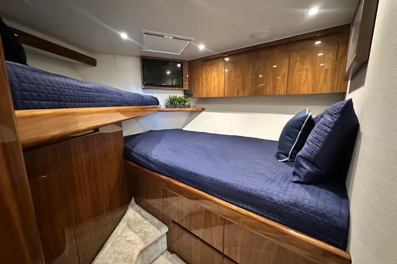 Wildcatter Yacht Photos Pics Luxurious cabin interior of 2017 Viking 55 Convertible yacht with wooden finishes and blue bedding.