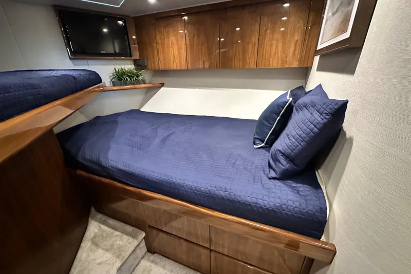 Wildcatter Yacht Photos Pics 2017 Viking 55 Convertible cabin with blue bedding, wooden cabinets, and a mounted TV.