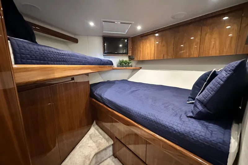 Wildcatter Yacht Photos Pics Luxurious cabin interior of 2017 Viking 55 Convertible yacht with wooden finishes and blue bedding.