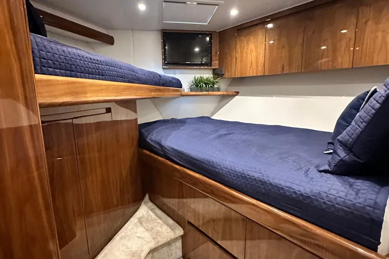 Wildcatter Yacht Photos Pics Luxurious cabin interior of 2017 Viking 55 Convertible yacht with wooden finishes and blue bedding.