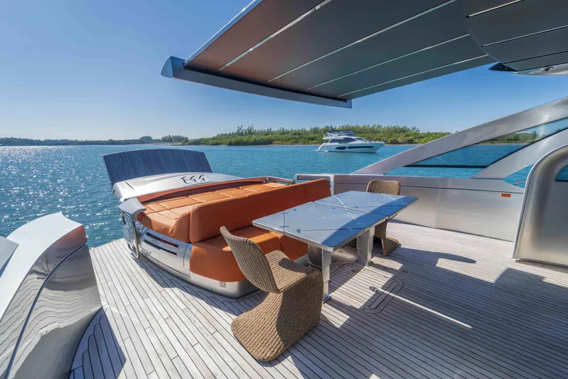 M Yacht Photos Pics Luxurious 2018 Pershing 70 yacht deck with seating and dining area, overlooking serene waters.