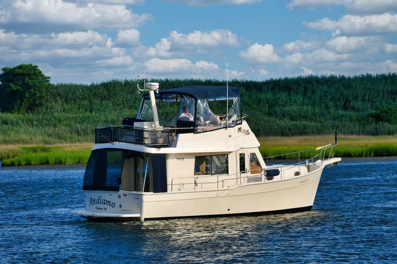  Yacht Photos Pics 2008 Mainship 34 Trawler cruising on a scenic river with lush greenery.