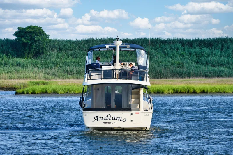  Yacht Photos Pics 2008 Mainship 34 Trawler cruising on a scenic river with lush greenery.
