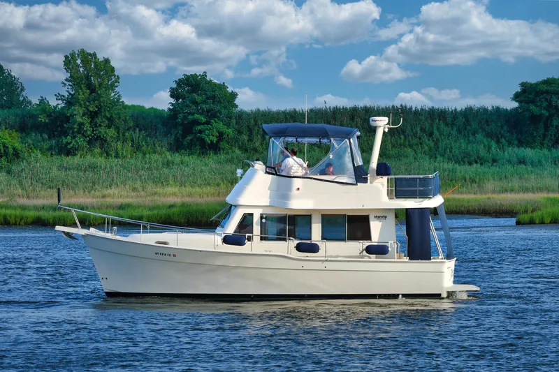 Yacht Photos Pics 2008 Mainship 34 Trawler cruising on a scenic river with lush greenery.