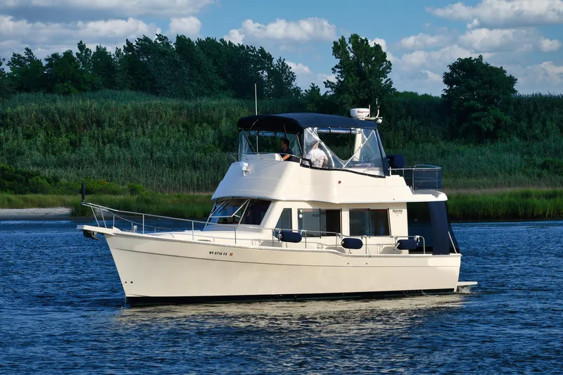  Yacht Photos Pics 2008 Mainship 34 Trawler cruising on a serene river with lush green backdrop.