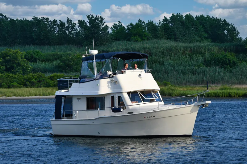  Yacht Photos Pics 2008 Mainship 34 Trawler cruising on a scenic river with lush greenery.