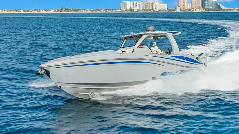  Yacht Photos Pics 2022 Deep Impact 399 Cabin boat cruising on open water near a city skyline.