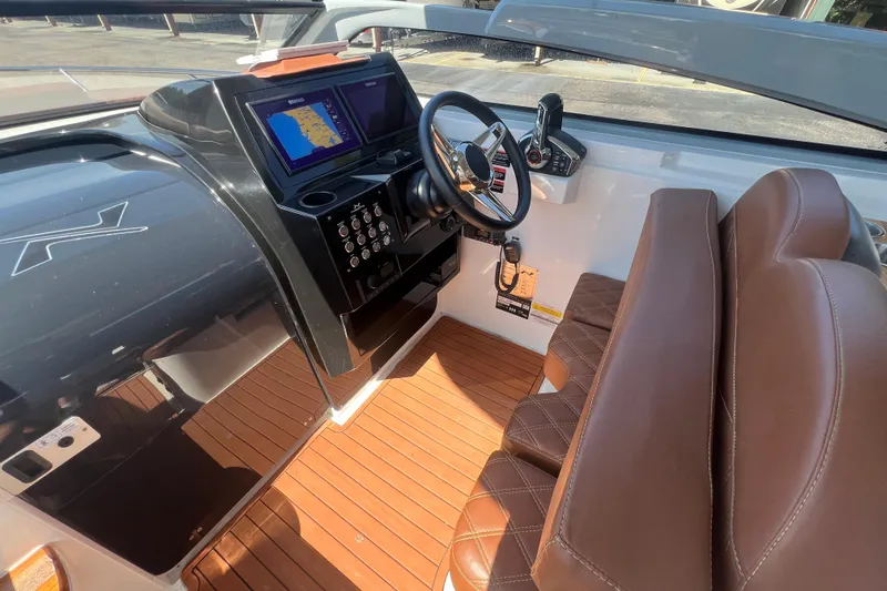  Yacht Photos Pics 2024 NX Boats 290 Exclusive cockpit with brown leather seats and modern navigation system.