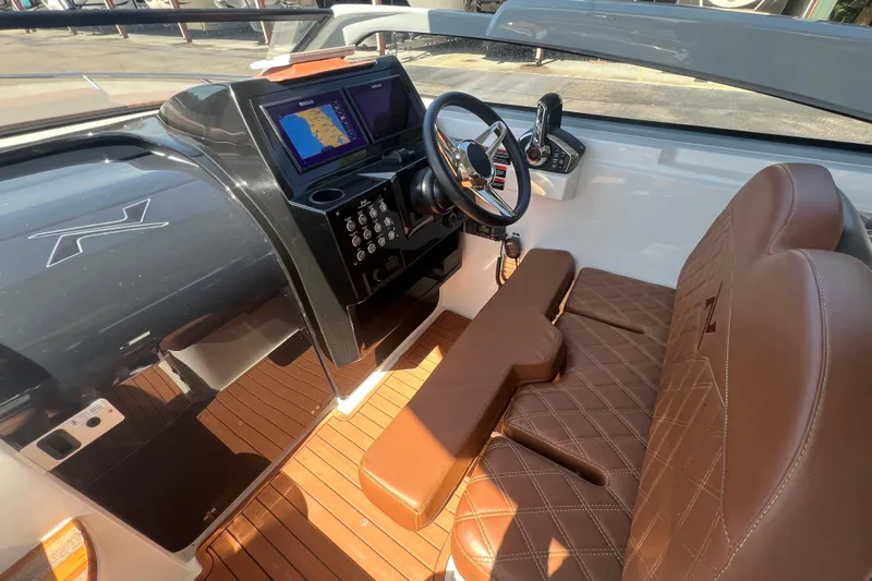  Yacht Photos Pics 2024 NX Boats 290 Exclusive cockpit with brown leather seats and modern dashboard.