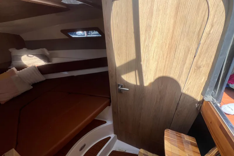  Yacht Photos Pics Interior cabin of 2024 NX Boats 290 Exclusive with wooden door and cozy seating area.