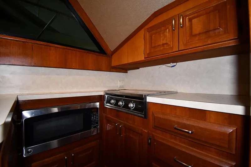 Patience III Yacht Photos Pics 1988 Viking 48 Convertible yacht kitchen with wooden cabinets, microwave, and stovetop.