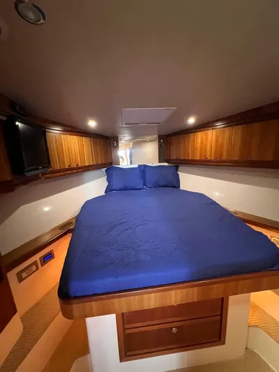 No Name Yacht Photos Pics 2009 Bertram Convertible cabin interior with blue bedding and wooden cabinetry.