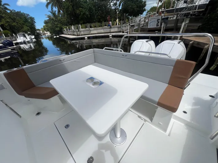  Yacht Photos Pics 2025 Beneteau Flyer 9 SUNdeck with spacious seating and table, docked by a serene canal.