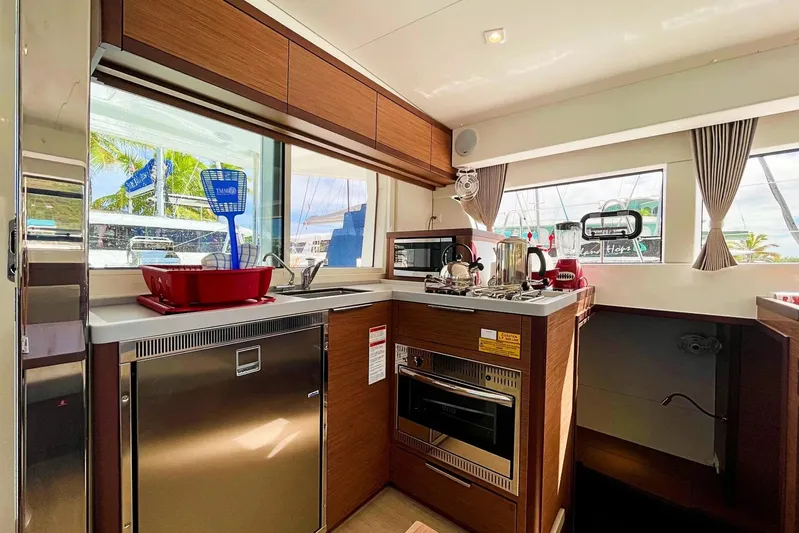 Noble Shadow Yacht Photos Pics Modern kitchen interior of 2022 Lagoon 40 catamaran with appliances and large windows.