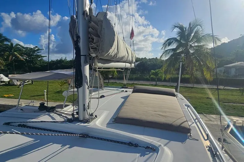 Noble Shadow Yacht Photos Pics 2022 Lagoon 40 catamaran deck with sails, palm trees, and blue sky background.