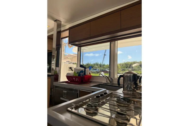 Noble Shadow Yacht Photos Pics Interior of 2022 Lagoon 40 yacht kitchen with stove, sink, and window view.