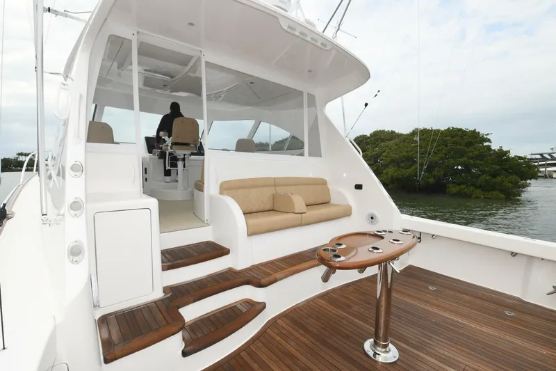 Galati Yacht Sales Trade Yacht Photos Pics 2022 Viking 44 Sport Coupe yacht with teak deck and seating area, docked near lush greenery.