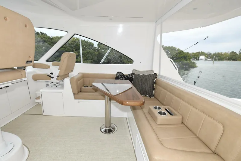 Galati Yacht Sales Trade Yacht Photos Pics 2022 Viking 44 Sport Coupe interior with beige seating and table, overlooking water.