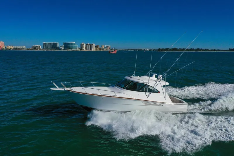 Galati Yacht Sales Trade Yacht Photos Pics 2022 Viking 44 Sport Coupe cruising on open water with city skyline in background.