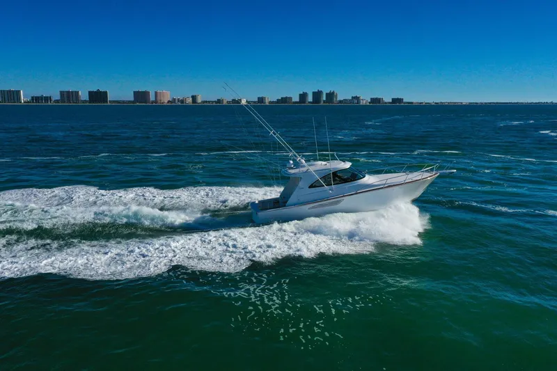 Galati Yacht Sales Trade Yacht Photos Pics 2022 Viking 44 Sport Coupe cruising on open water with city skyline in background.