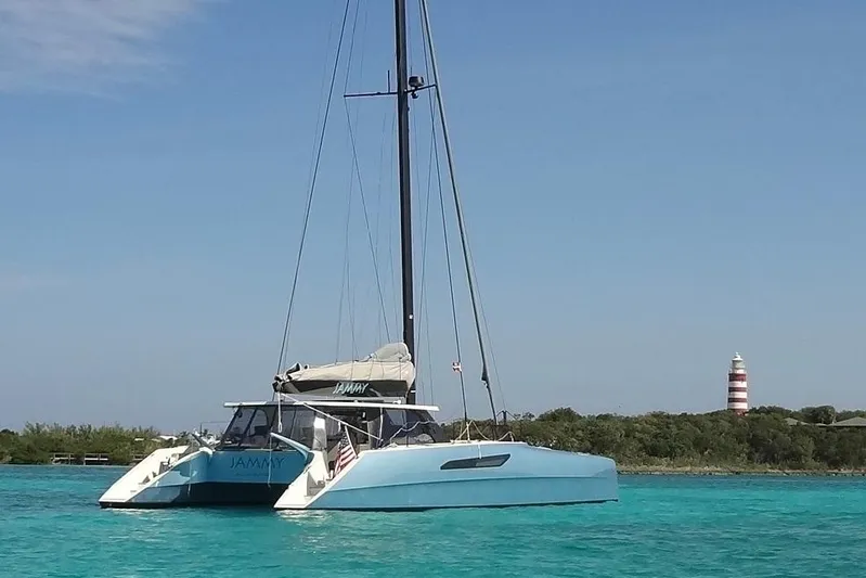 Jammy Yacht Photos Pics 2015 Gunboat 57' catamaran sailing near a lighthouse in clear blue waters.