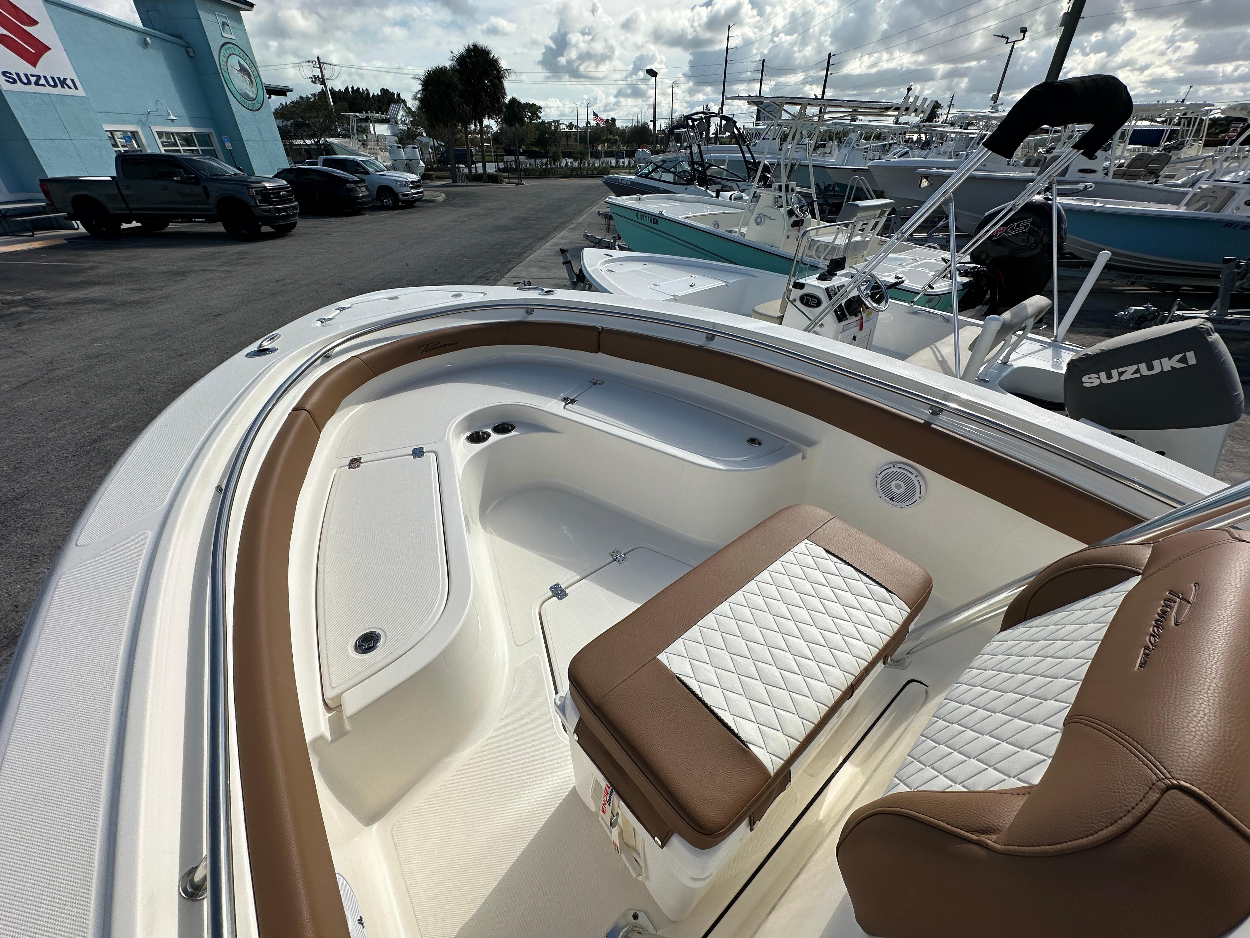 2025 Pioneer 222 Sportfish boat interior with brown and white seating, docked at a marina.