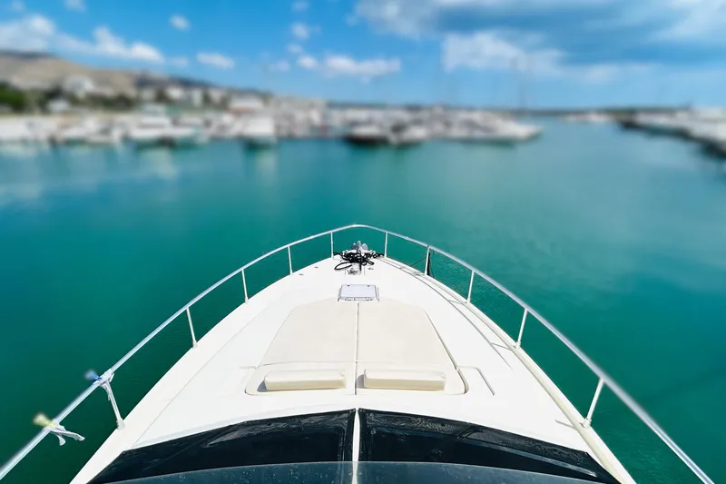  Yacht Photos Pics Ferretti Yachts 45 Altura 1992 cruising in a serene marina with clear blue waters.