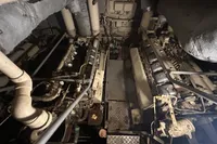 Engine room of a 1970 Custom Bootswerft Burmester 24 boat, showcasing dual engines and piping.