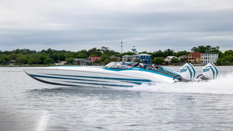  Yacht Photos Pics 2024 MTI 440X speedboat cruising on a calm lake with scenic shoreline backdrop.