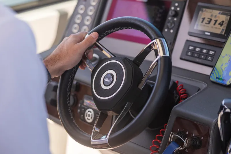 Yacht Photos Pics Steering wheel of 2022 Chaparral 300 OSX boat with dashboard controls and navigation display.