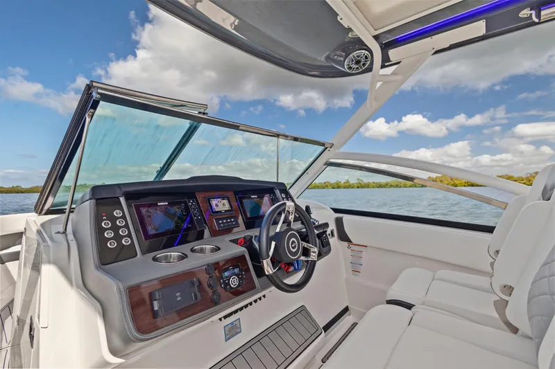  Yacht Photos Pics 2022 Chaparral 300 OSX boat cockpit with modern dashboard and steering wheel on open water.