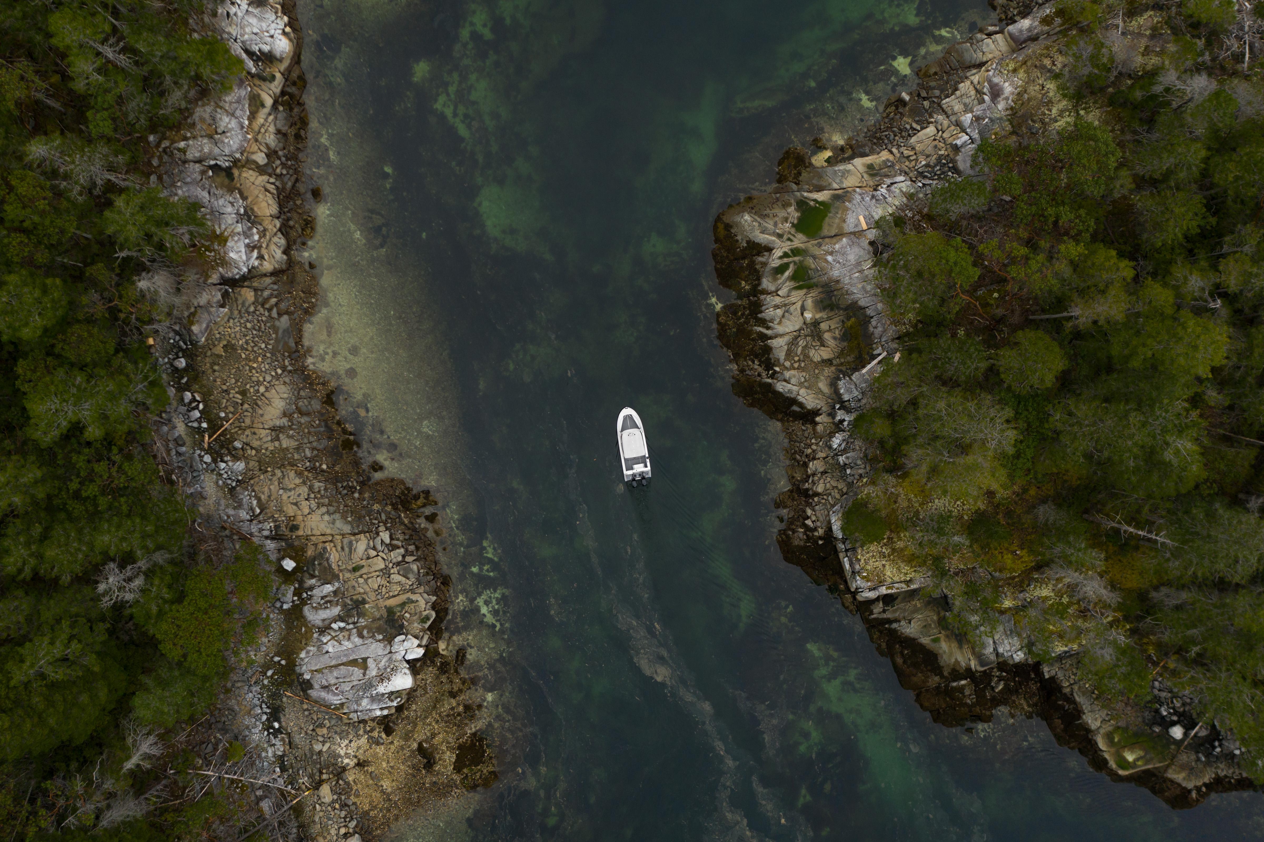 Aerial view of 2025 Jasper Marine Defender 22 navigating narrow waterway between rocky cliffs.