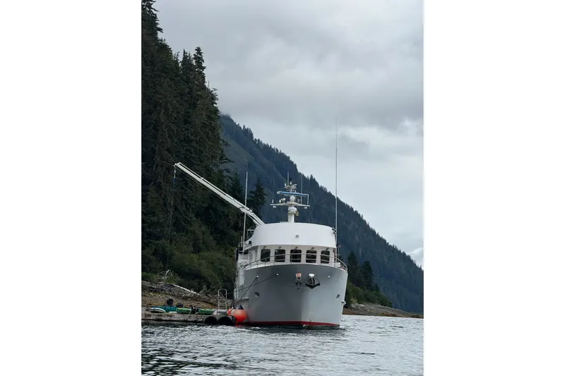 Evening Star Yacht Photos Pics Cape Horn 2003 Trawler anchored near forested shoreline under cloudy sky.