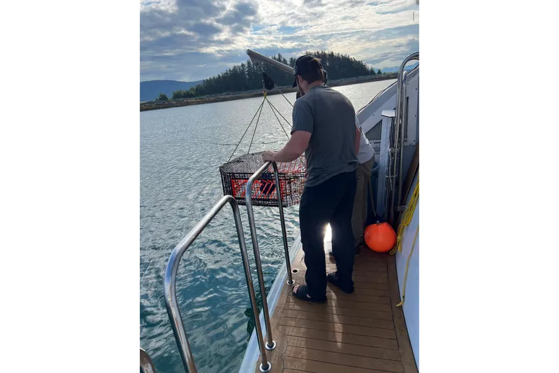 Evening Star Yacht Photos Pics Man on 2003 Cape Horn Trawler fishing with trap in scenic waters.