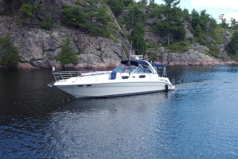  Yacht Photos Pics 2002 Sea Ray 410 Sundancer yacht cruising near rocky shoreline with lush greenery.