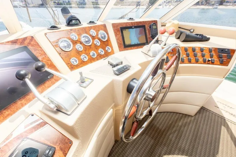 Adventures Await Yacht Photos Pics Pilothouse interior of 2004 Meridian 490, featuring steering wheel and navigation controls.