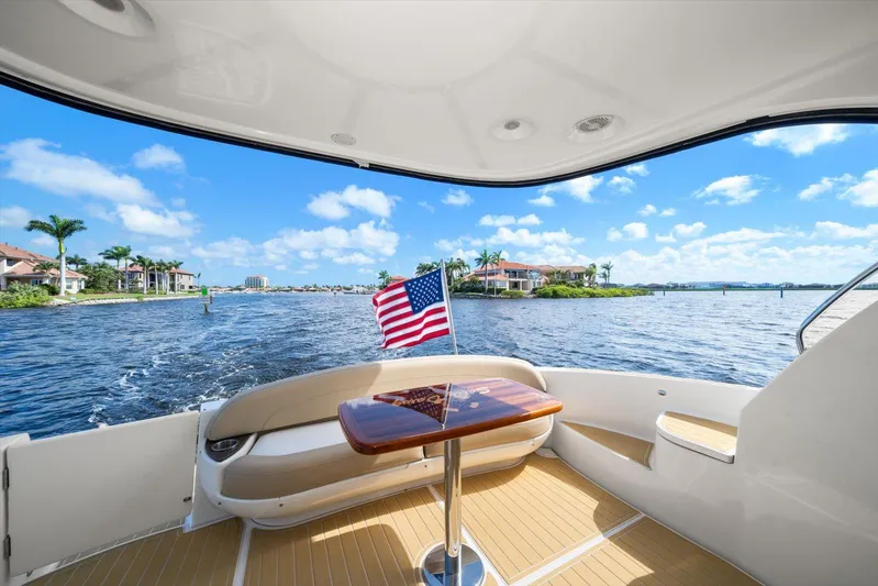 Gail’s Storm IV Yacht Photos Pics 2015 Meridian 441 Sedan yacht with American flag, cruising on a sunny day near waterfront homes.