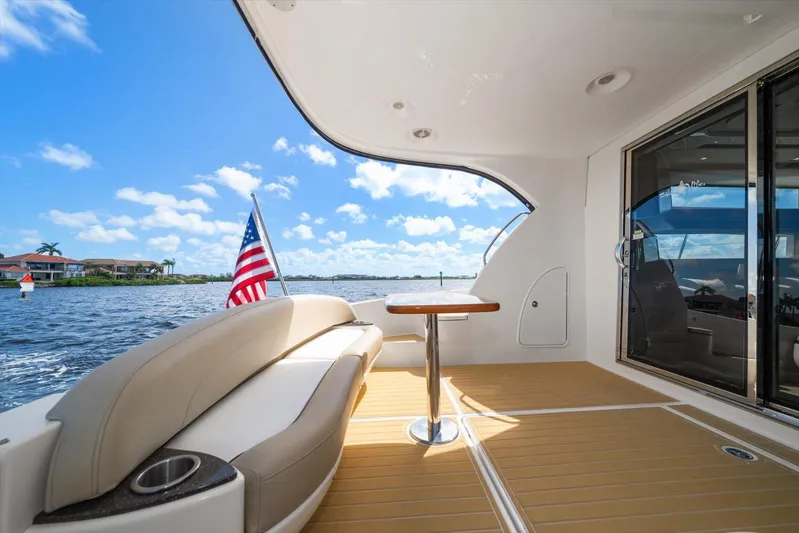 Gail’s Storm IV Yacht Photos Pics 2015 Meridian 441 Sedan yacht deck with seating, table, and American flag on a sunny day.