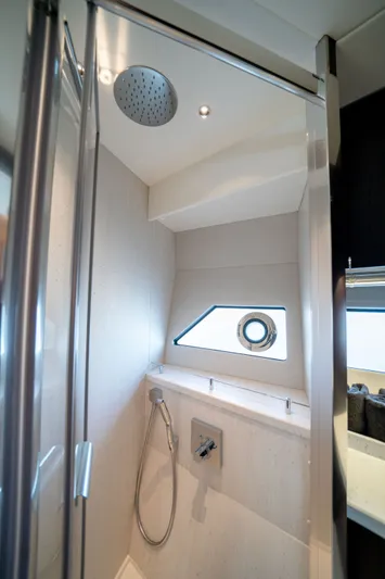 Tango Lima Yacht Photos Pics Luxurious shower area in 2022 Sunseeker 60 Predator EVO yacht, featuring modern fixtures and porthole window.