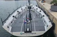 Sleek TP52 sailboat "Blue Carbon" docked, featuring modern design and branding, 2007 model.