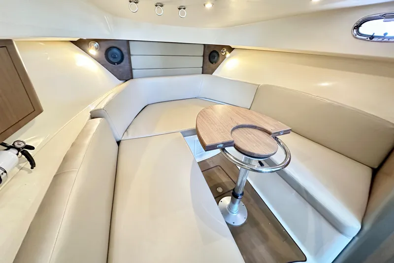 Extra Vagancia Yacht Photos Pics 2015 Boston Whaler 315 Conquest cabin interior with beige seating and wooden table.