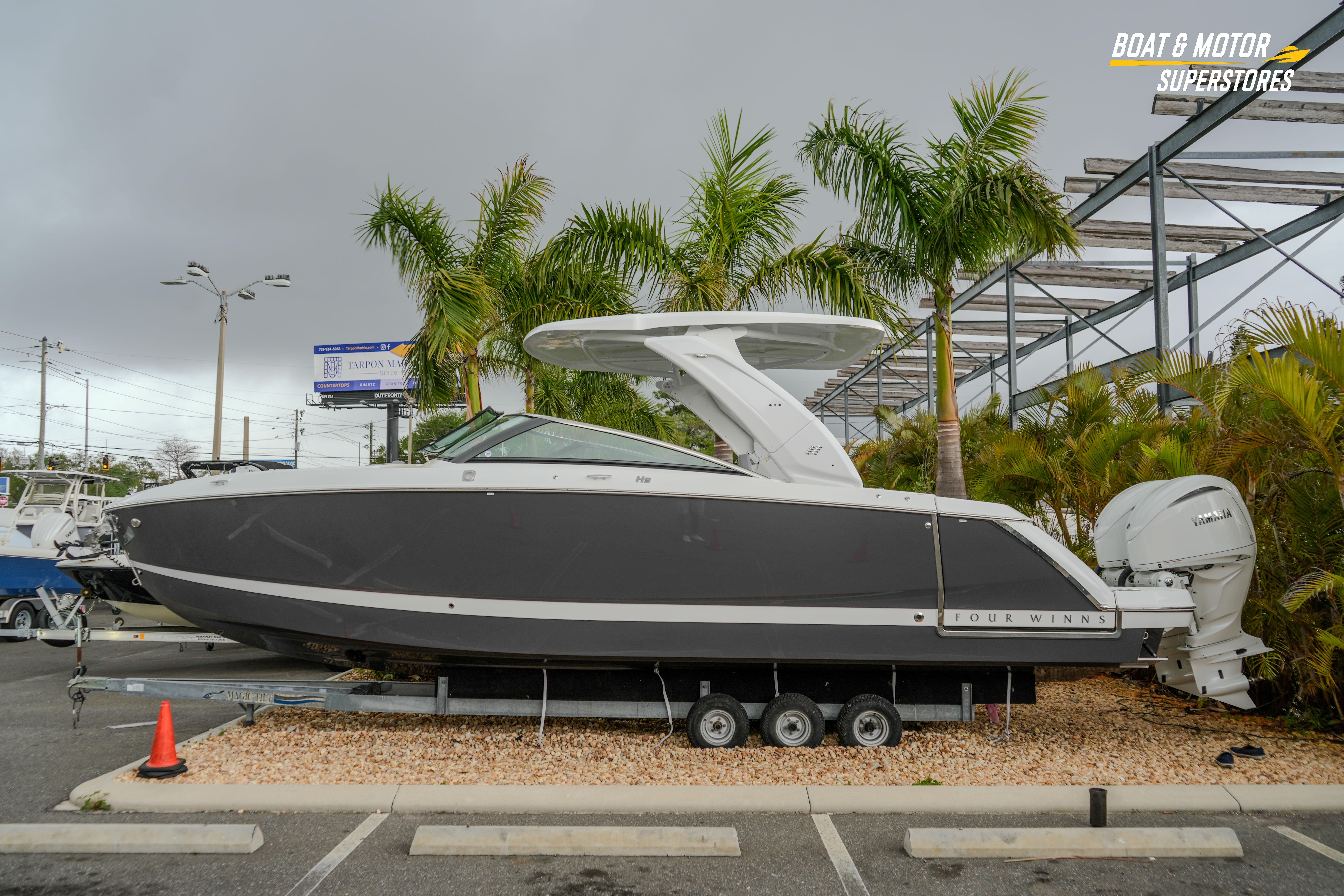 2026 Four Winns H9 OB boat displayed outdoors with palm trees in the background.