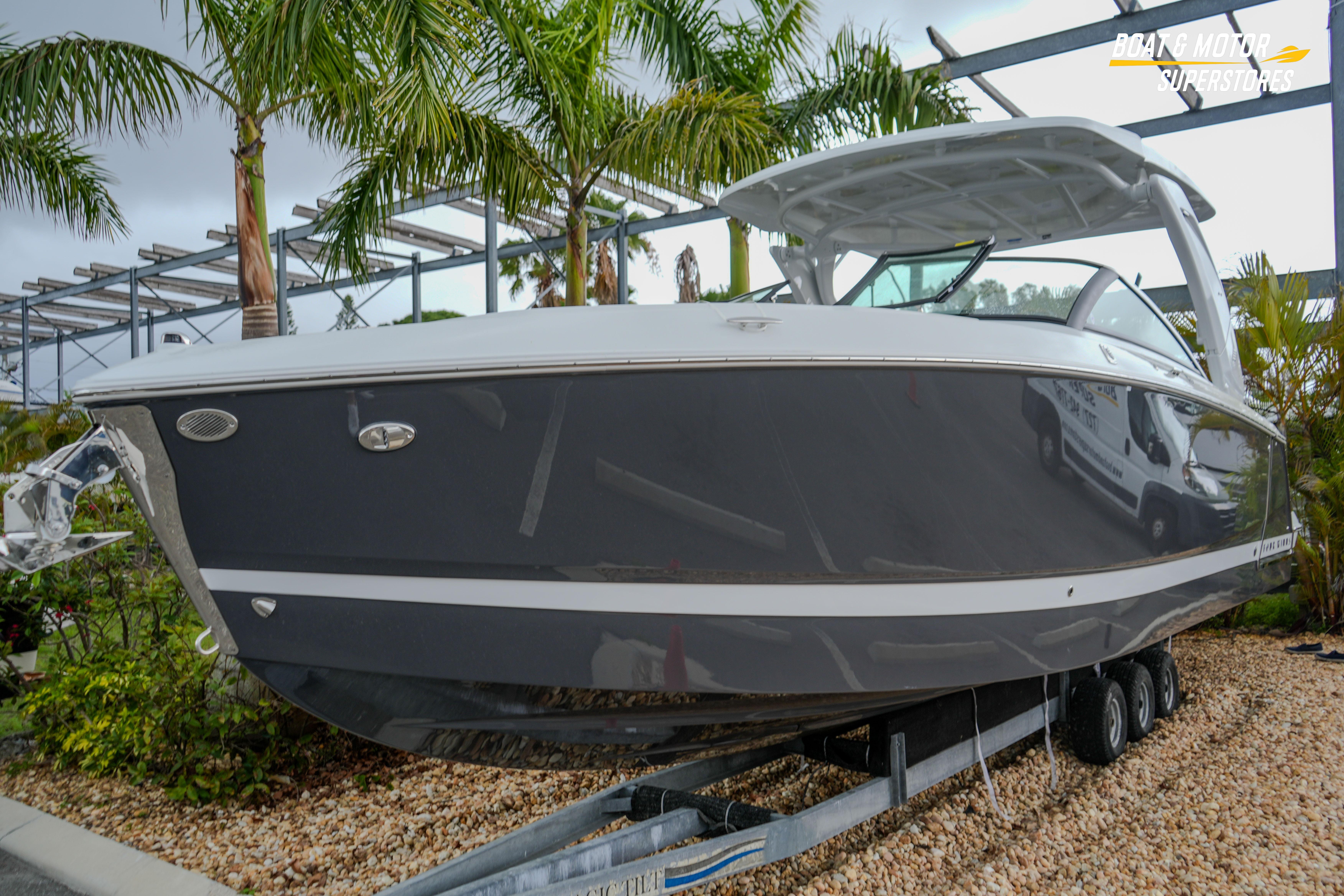 2026 Four Winns H9 OB boat on trailer, surrounded by palm trees.