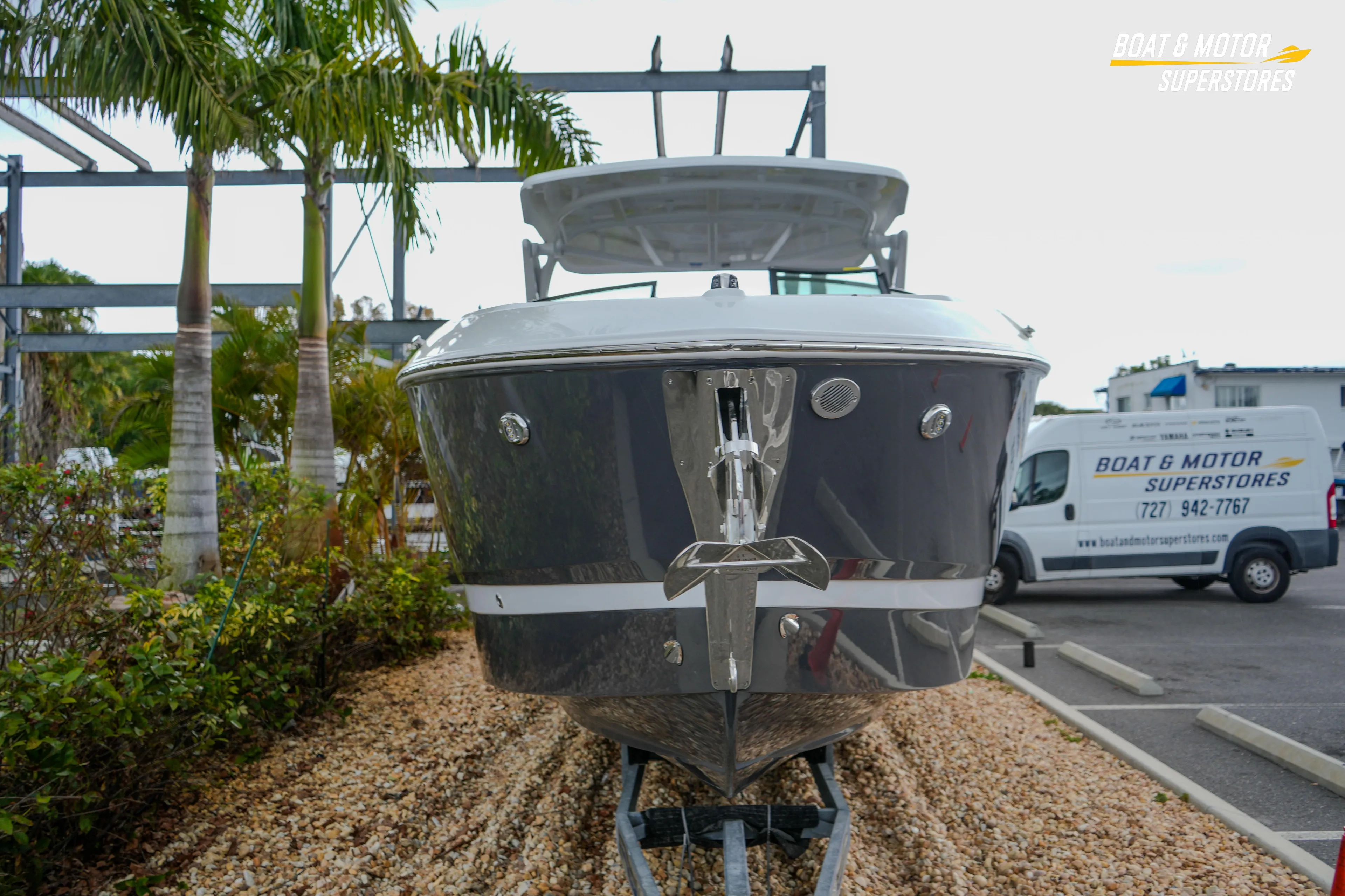 2026 Four Winns H9 OB boat displayed at dealership with palm trees and service van.