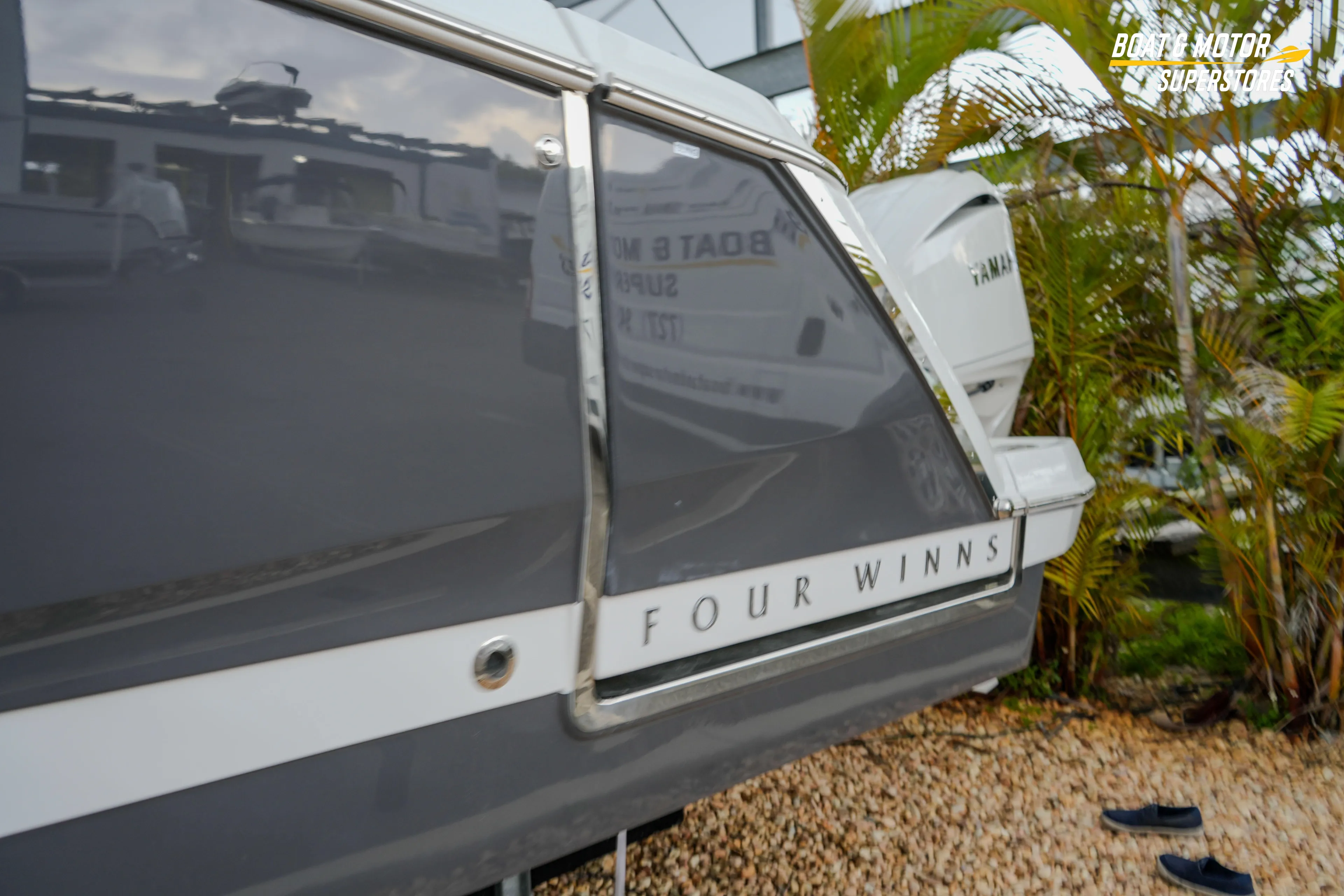 2026 Four Winns H9 OB boat, sleek design, parked outdoors near palm trees.