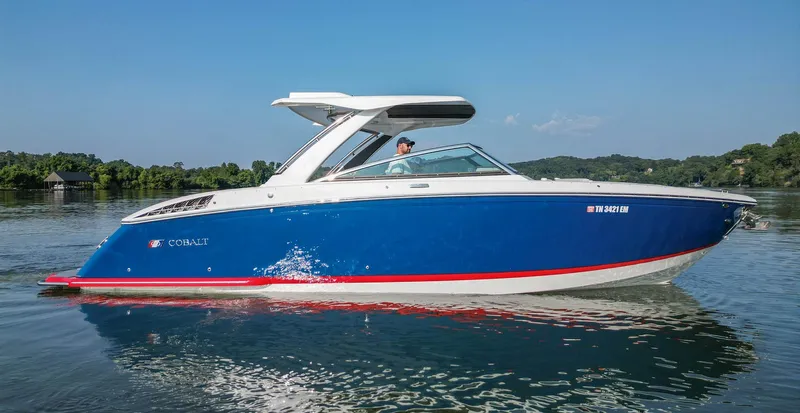  Yacht Photos Pics 2023 Cobalt R33 boat cruising on a calm lake under a clear blue sky.