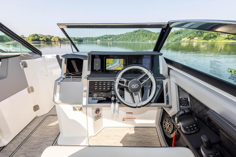  Yacht Photos Pics Interior view of 2023 Cobalt R33 boat cockpit with steering wheel and navigation system.