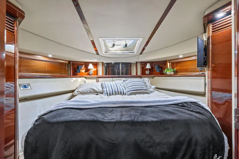 The Blue Fish Yacht Photos Pics Luxurious 2007 Sea Ray 52 Sedan Bridge yacht bedroom with elegant wood finishes and cozy bedding.
