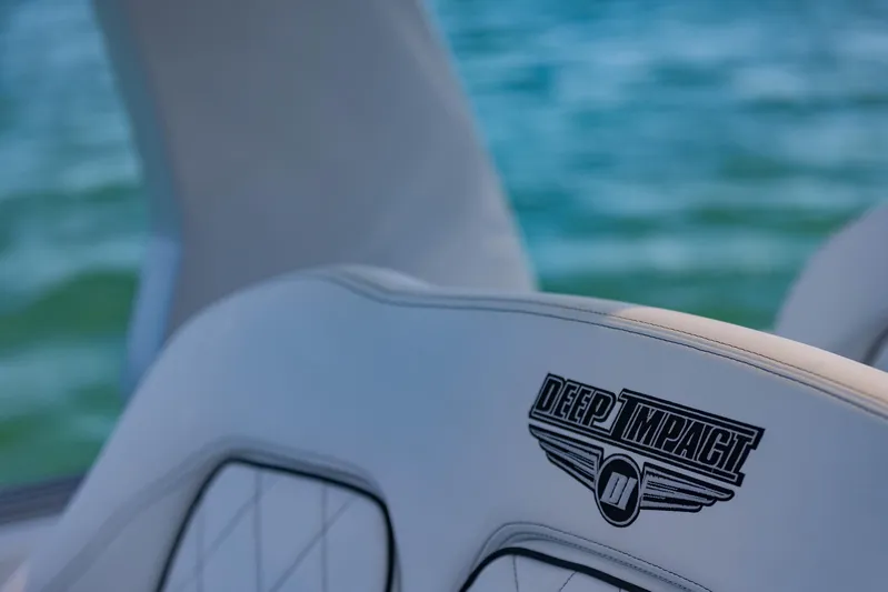  Yacht Photos Pics 2024 Deep Impact 399 Sport boat seat with logo, against a serene water backdrop.
