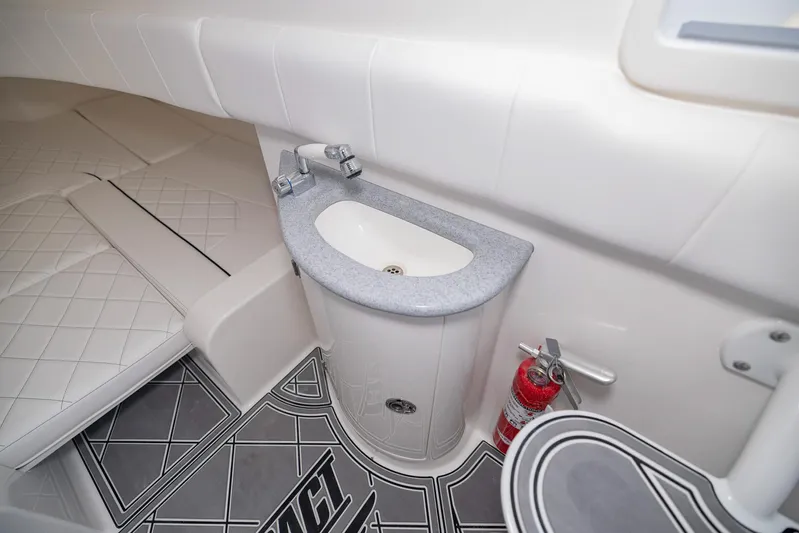  Yacht Photos Pics 2024 Deep Impact 399 Sport interior with sink, fire extinguisher, and cushioned seating.